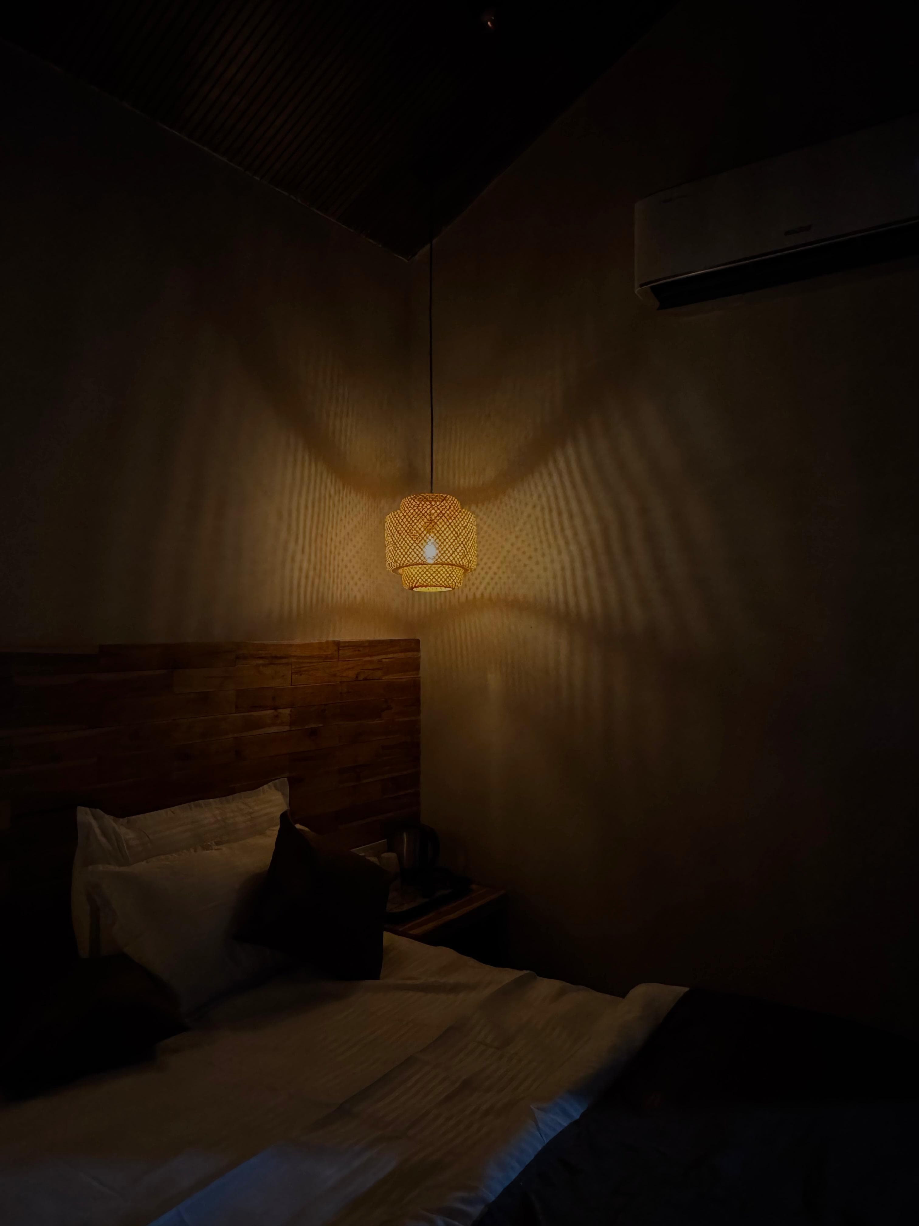 Warm pendant light above a resort bed