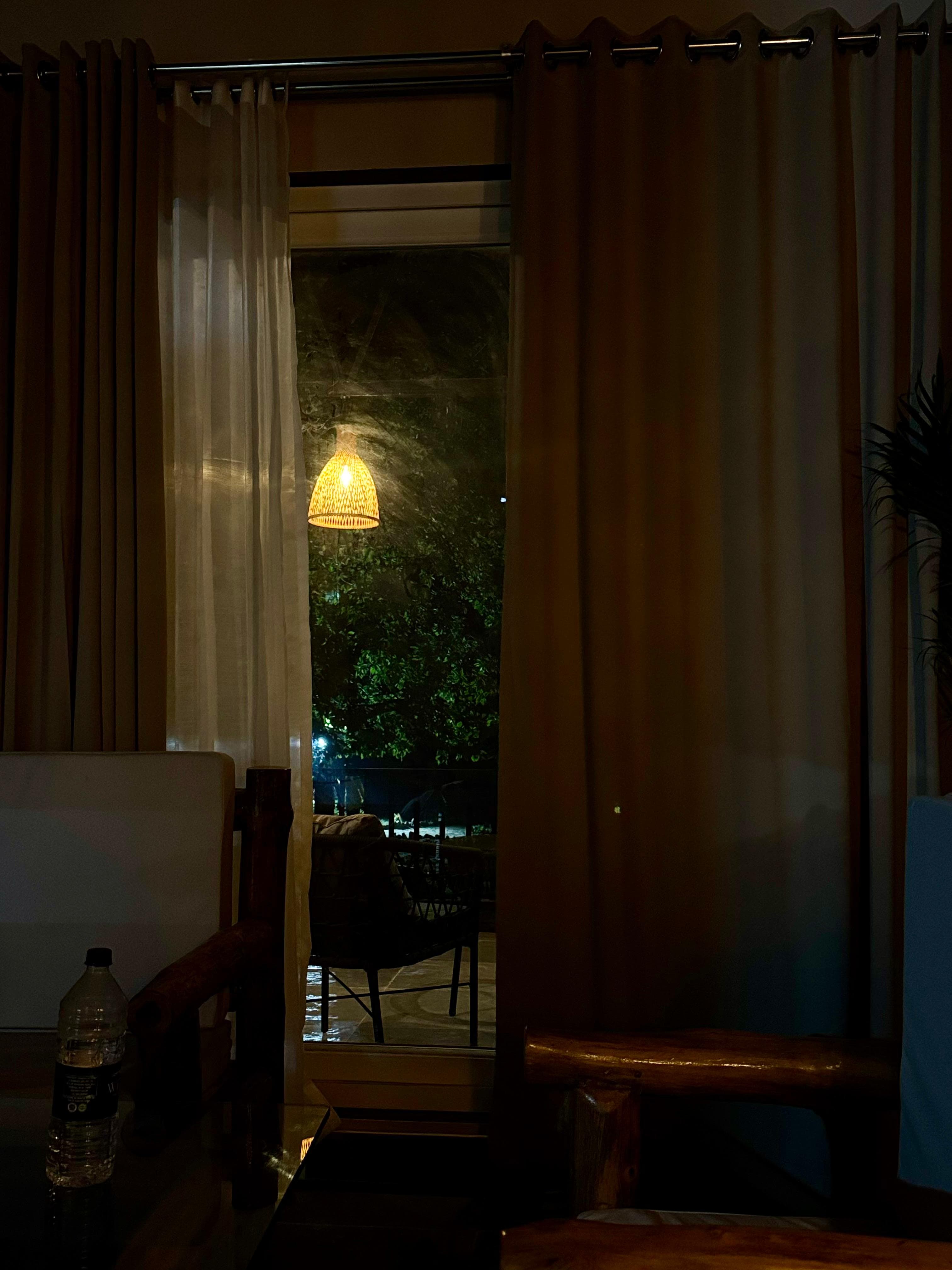 Night garden view framed by resort curtains